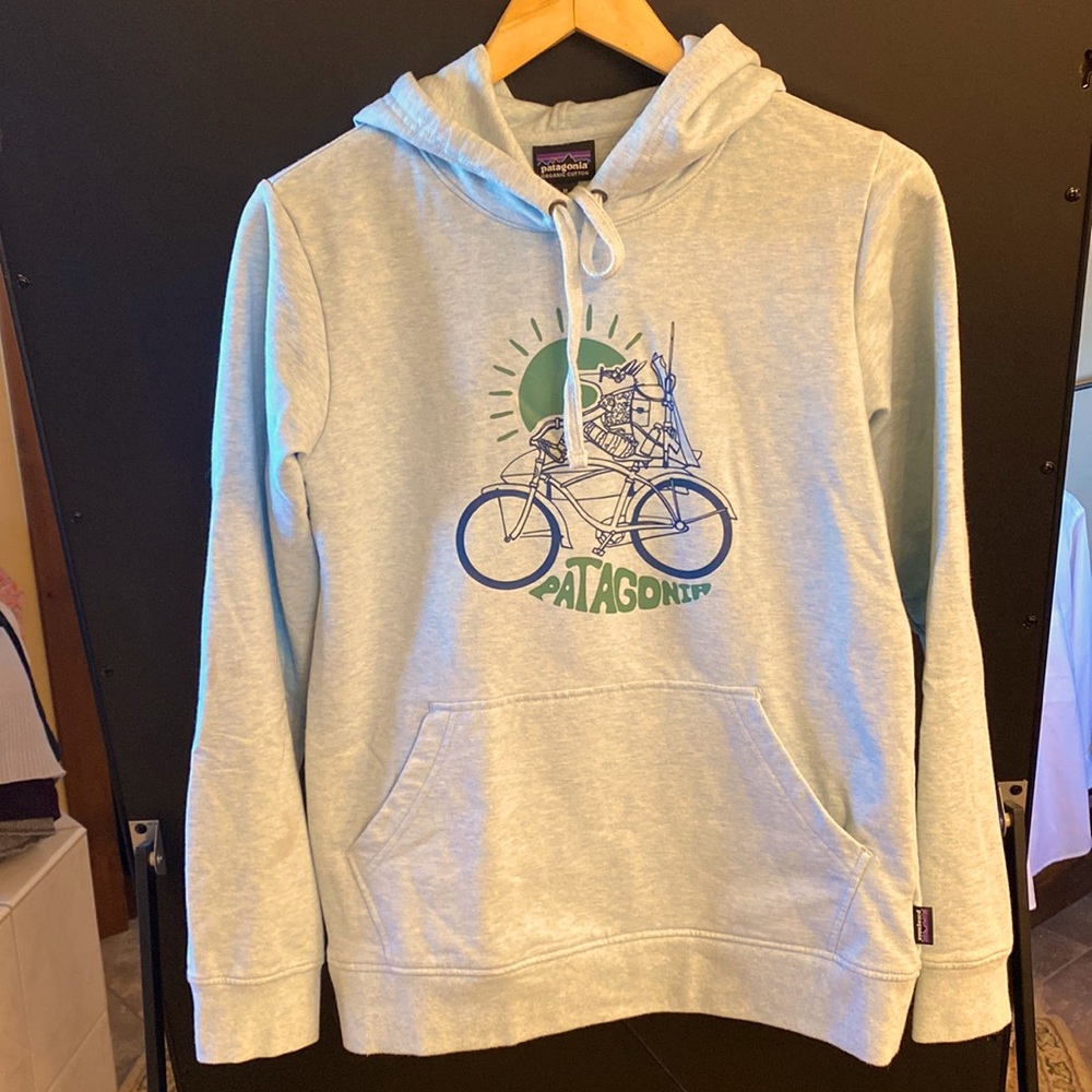 Patagonia hooded sweatshirt, green, with fox riding a bicycle graphic.